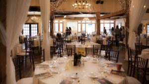 Elegant banquet hall with round tables set for an event, beautifully decorated with lights and flowers—a perfect setting for seamless event planning, with guests mingling in the background.