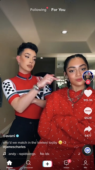 Two people posing together indoors for a TikTok video, both wearing patterned red outfits, ready to create trending content.
