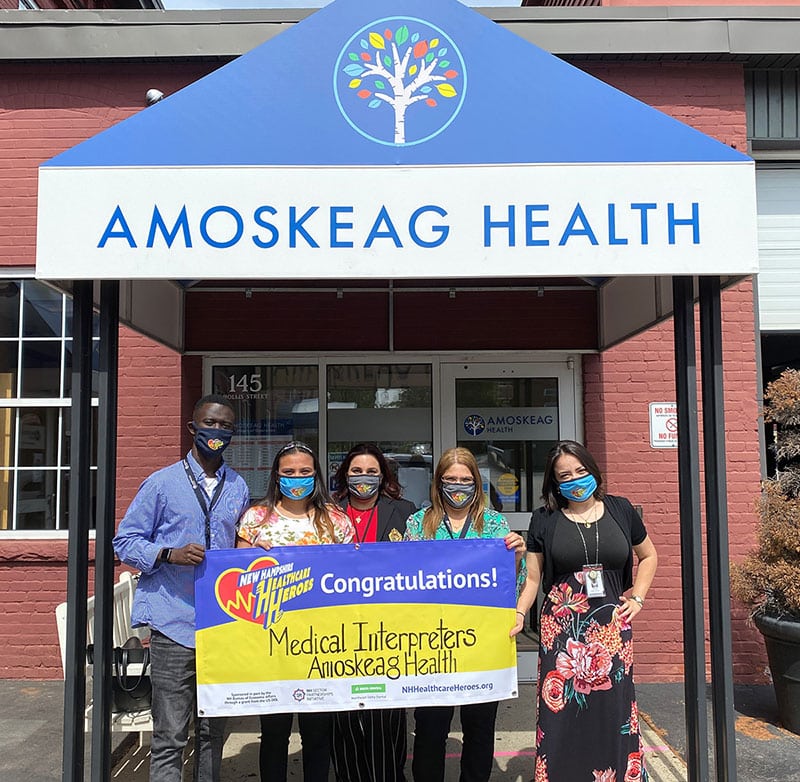 Five people stand outside Amoskeag Health, holding a banner celebrating medical interpreters and showcasing the importance of healthcare branding in connecting communities.
