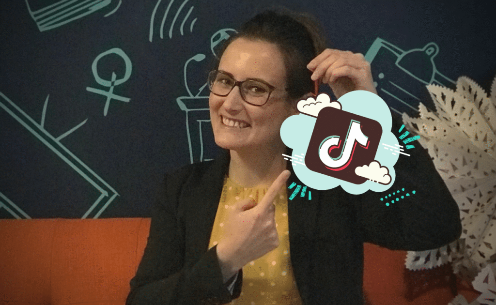 Woman smiling and pointing at a digital TikTok logo graphic, highlighting the power of social media marketing while sitting on an orange couch with a dark backdrop.