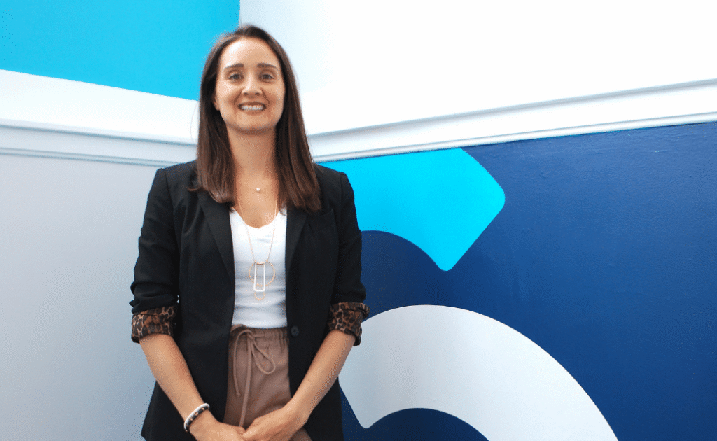Kristen Lestock stands next to Cookson Communications logo