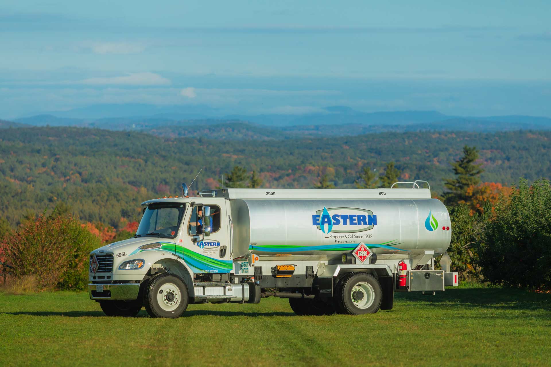 Eastern propane truck parked on grass with trees and mountains in the background under a blue sky.