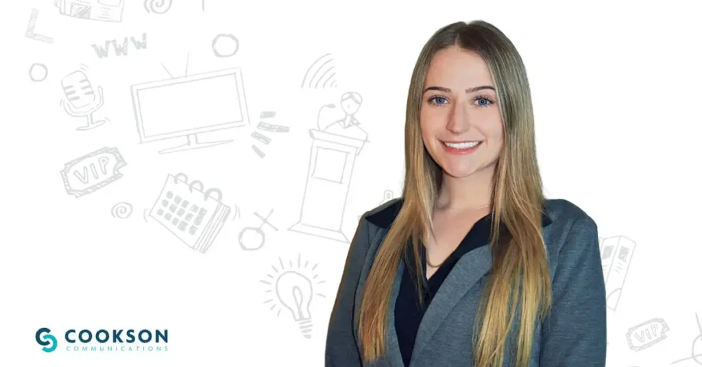 Woman in a gray blazer smiles in front of a white background with communications-themed doodles.