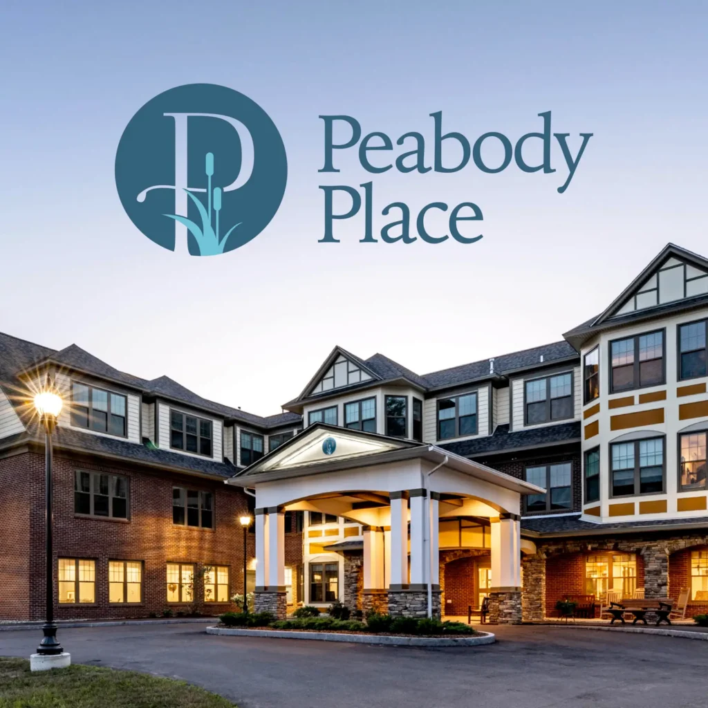 Exterior of Peabody Place assisted living facility at dusk, featuring the newly rebranding logo and the welcoming building entrance.