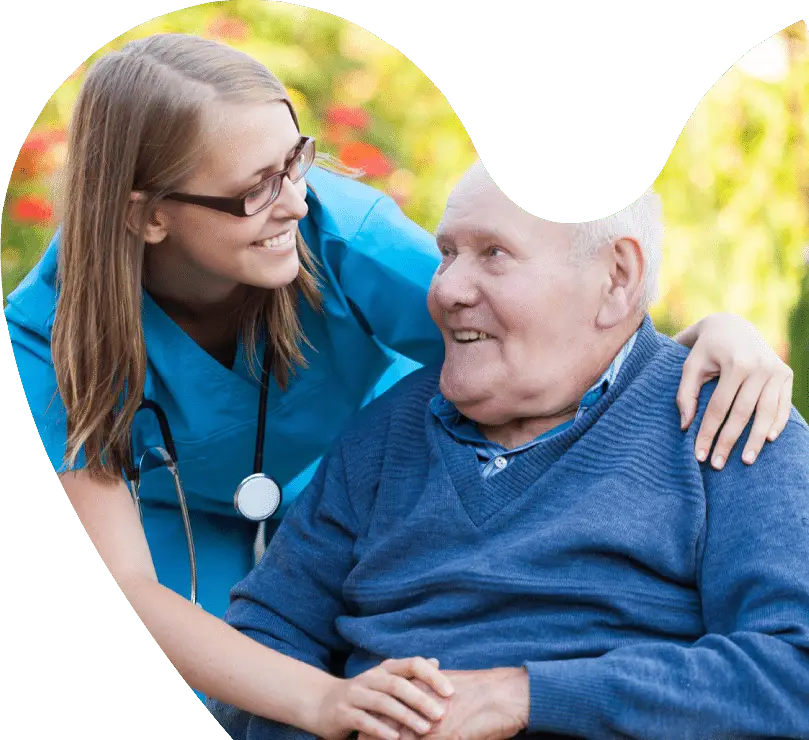 A nurse in blue scrubs smiles and talks with an elderly man sitting in a wheelchair outdoors, creating a perfect scene for a rebranding case study focused on compassionate care.