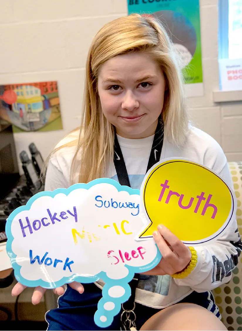 Young woman holding signs that say truth and a thought bubble with words like Hockey, Work, Subway, Music, Sleep.