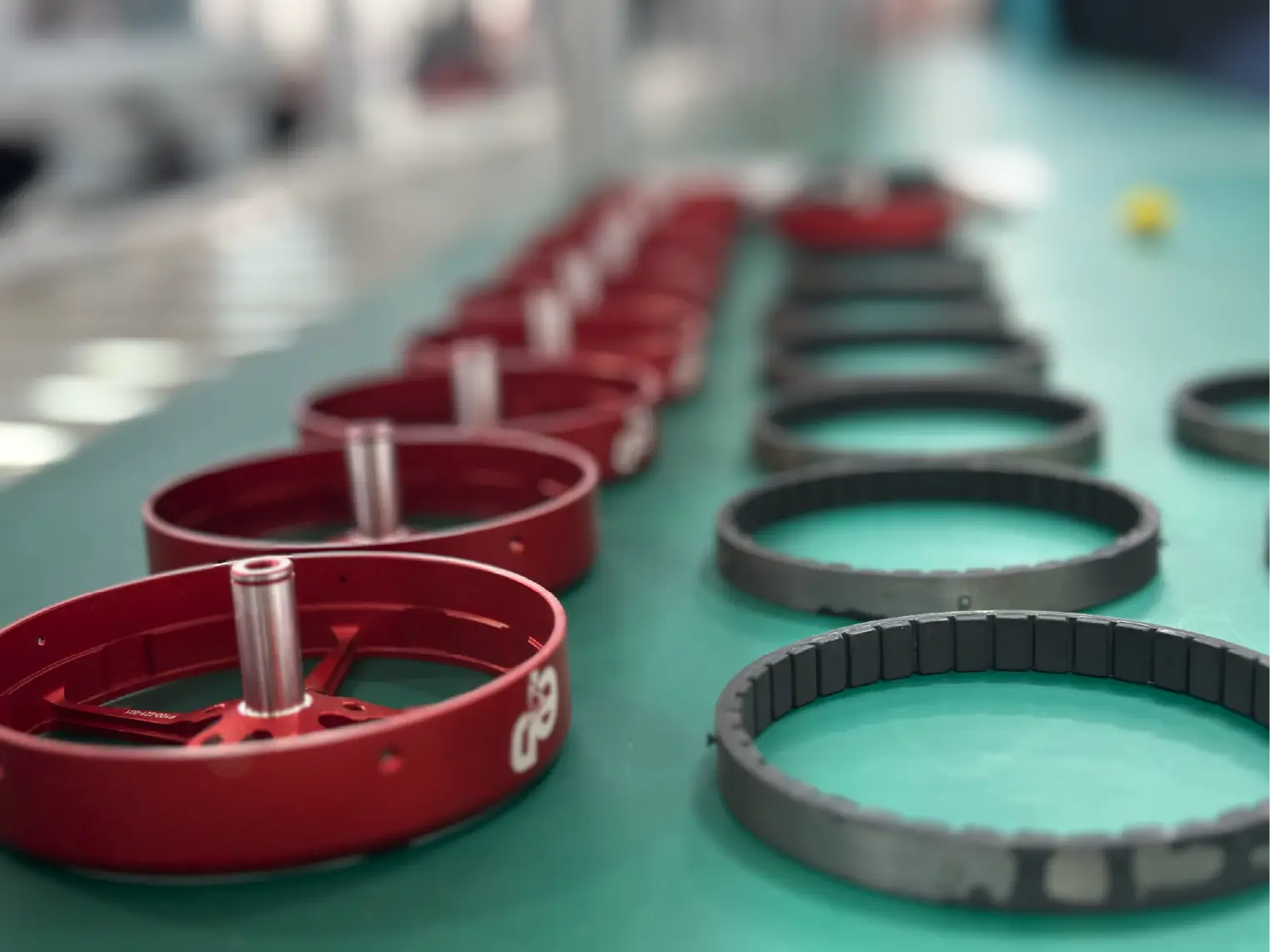 Red and black mechanical rings lined up on a green factory workbench in a row.