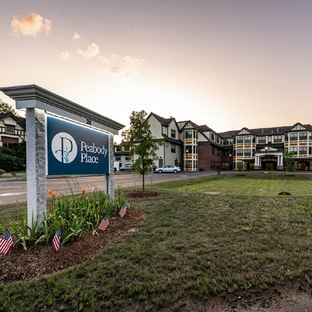 A sign for Peabody Place stands in front of a large building at sunset, with small American flags nearby, reflecting the brand strategy that emphasizes community and local pride.