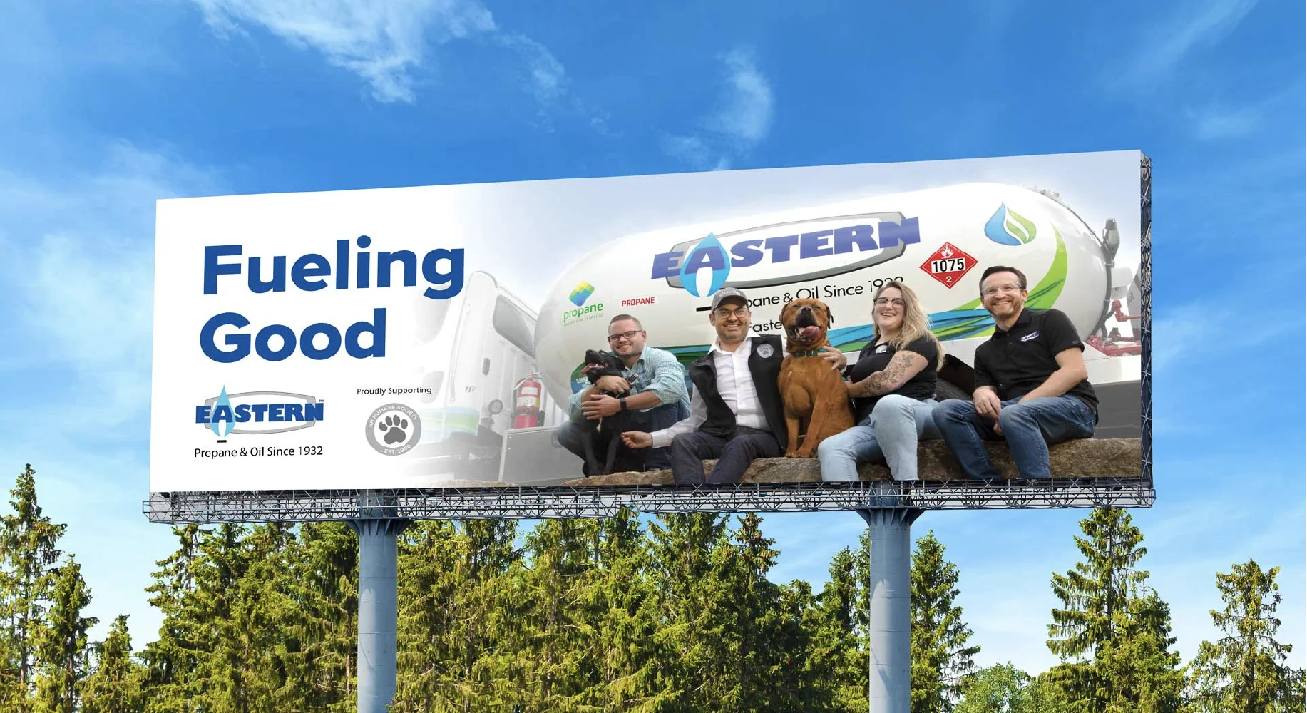 Creative billboard featuring four people and two dogs seated on hay, with the text Fueling Good and Eastern Propane branding.