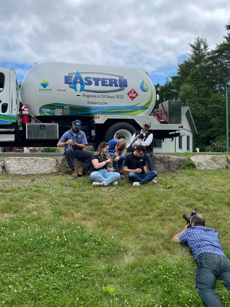Five people sit on grass near an Eastern propane truck as a photographer captures the moment, reflecting the team spirit behind effective growth marketing.