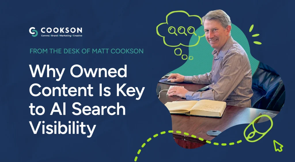 Smiling man at desk with a notebook and computer; text reads “Why Owned Content Is Key to Boosting AI Search Visibility.”.