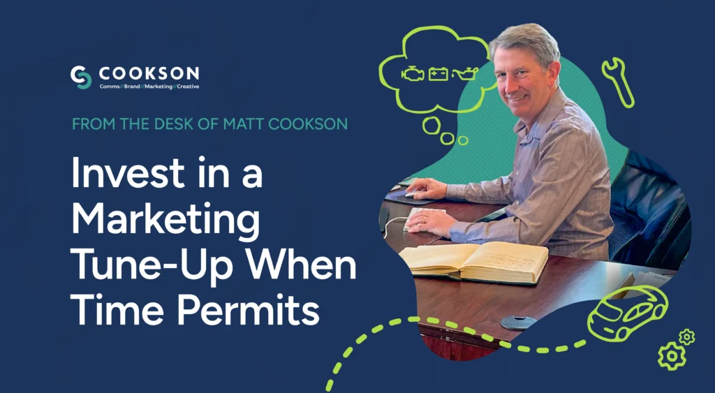 Man smiling at desk with notebook, beside text: Invest in a Marketing Tune-Up When Time Permits.
